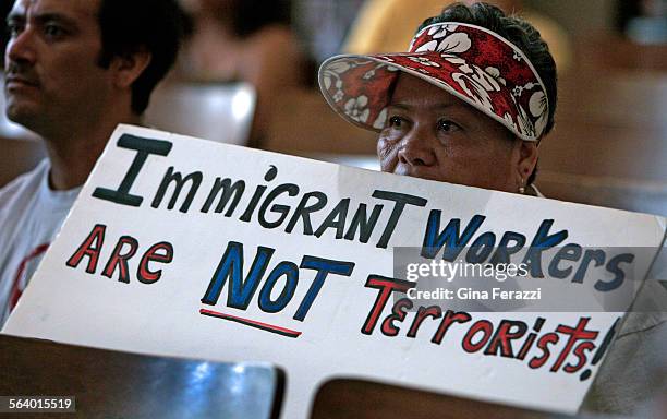 Maria Tejada keeps her protest sign close while attending a proimmigrant rights group prayer at Echo Park Methodist Church before marching in...