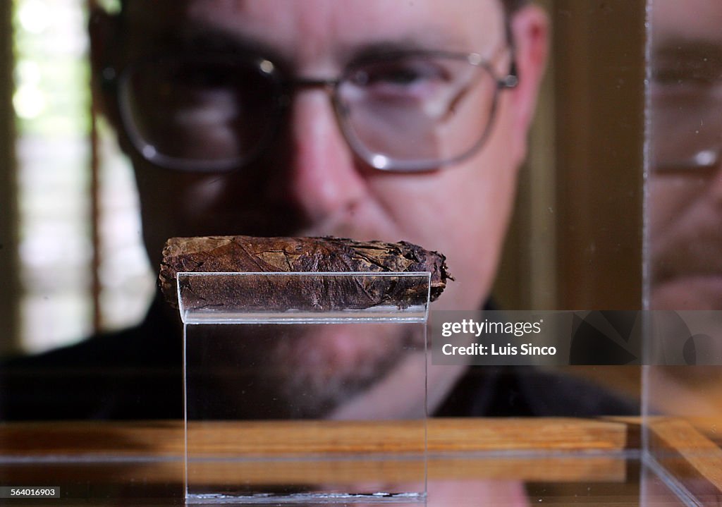 Pasadena resident Terry Cannon looks into a glass case containing the butt of a cigar smoked by bse