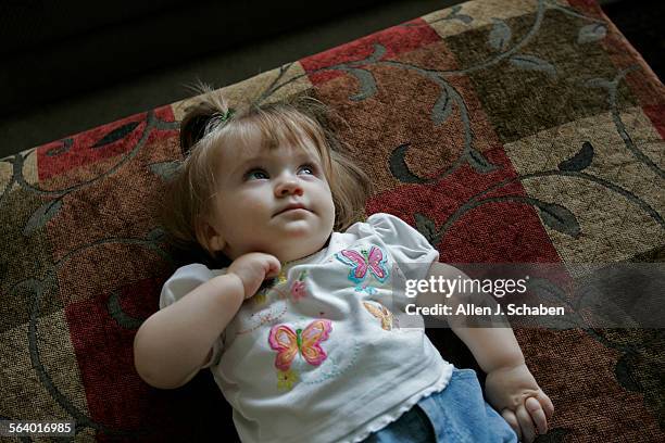Monthold Krystie Anna KarlSteiger, who can't walk, peers out the window in between playing with her dads Rick Karl and Bruce Steiger at their...