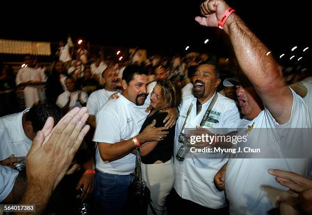 Alejandro "Chino" Vega with his wife Jessenia and members of the UCE Car Club celebrate his win for the Best Car in Show award Sunday night following...