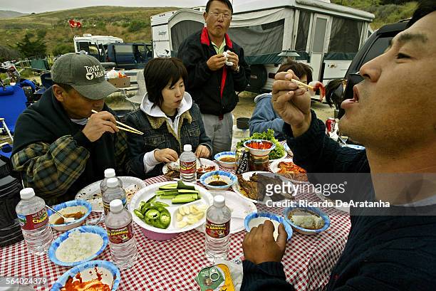 Young Kim , right, of Los Angeles, ready to bite on a, freshly caught perch, sashimi, during breakfast at Jalama Beach County Park campground....