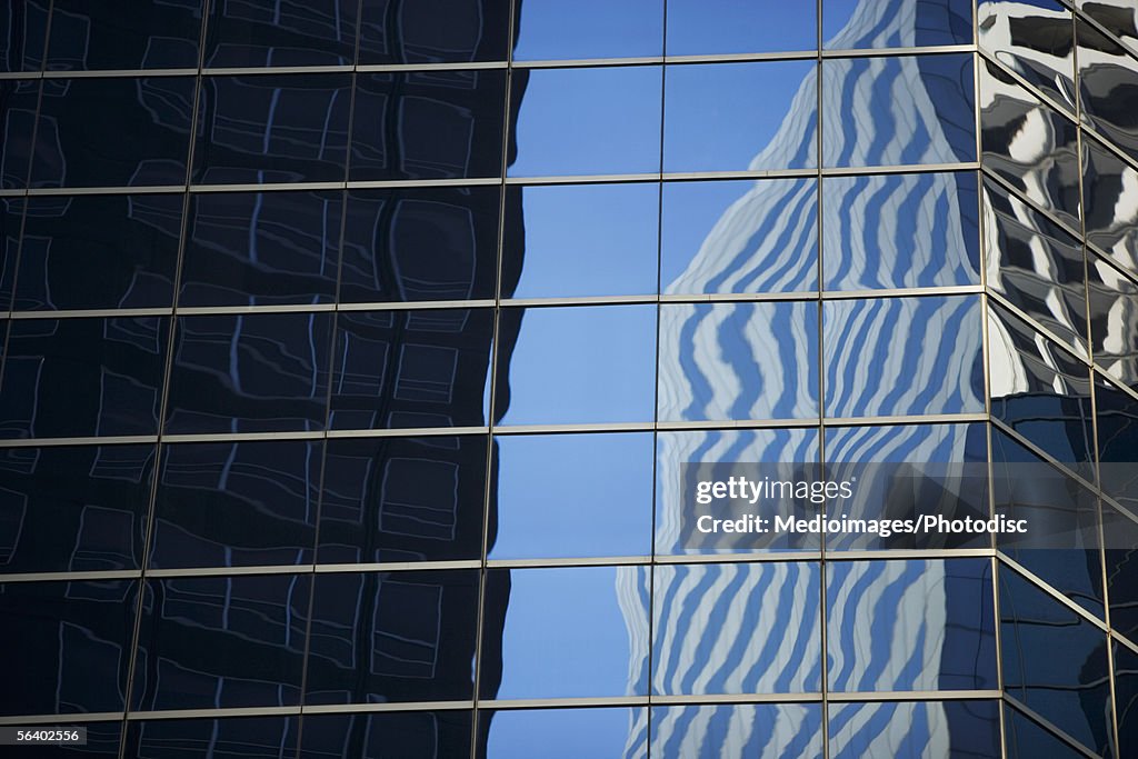 Close-up of windows on skyscraper, with reflection of another skyscraper in New York City, NY, USA