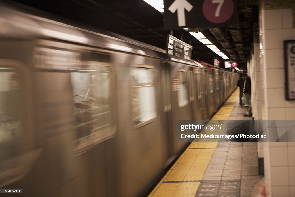 People waiting on subway platform as train goes by, New York City, NY, USA