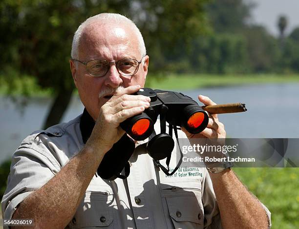 Tim Williams, dean of gator wrestling at Gatorland in Orlando, Florida use binocular as he searches for the alligator at Machado Lake in Ken Malloy...