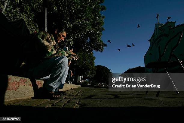 Pedro Agulez , who has been homeless for over one year sits on a curb at homeless camp across the street from Our Lady Queen of Angels Church La...