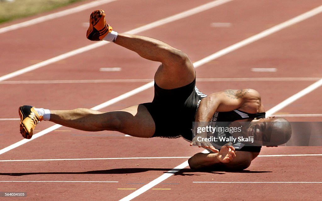 Sprinter Maurice Green falls to the track after pulling up in the 100m finals won by Justin Gatlin