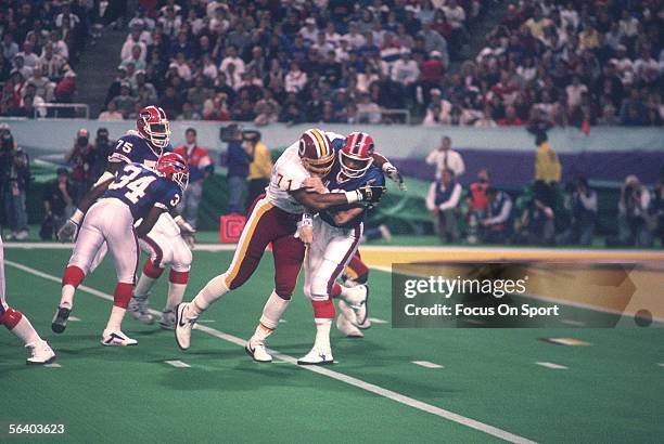Jim Kelly of the Buffalo Bills passes to a teammate but is tackled near the end zone during Super Bowl XXVI against the Washington Redskins at the...