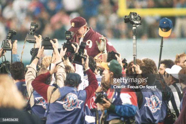 Coach Joe Gibbs of the Washington Redskins is held up by his teammates after winning the Super Bowl XXVI against the Buffalo Bills at the Metrodome...