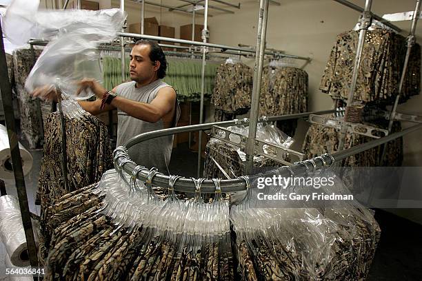 Oscar Perez wraps womens clothes at Holy Camp Clothing located in downtown Los Angeles. Some of the employees of owner Sam Hong receive minimum wage...