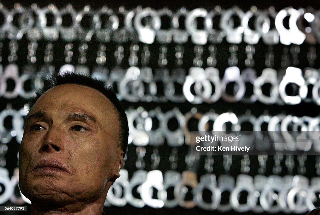 Photo of Chol Soo Lee, wrongfully convicted stands in front of handcuffs used during ceremony, 2006