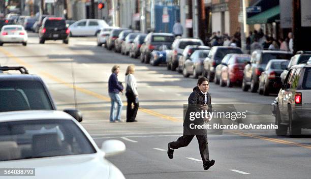 Doughboy's valet jaywalking across 3rd St. After backing up a vehicle a half block to park it at a meter. Story is about the parking crunch on 3rd...