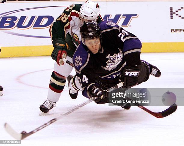 Kings Alexander Frolov dives for a puck near the goal with Minnesota Wild Todd White on his back during the first period at Staples Center in Los...