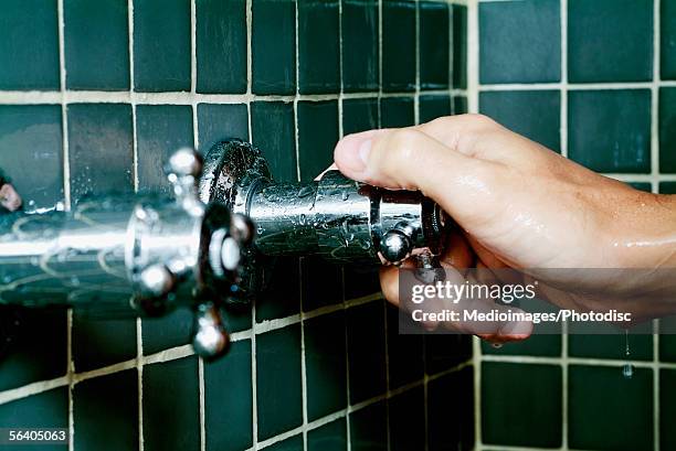 close-up of a person's hand turning a shower knob - shower tap stock pictures, royalty-free photos & images