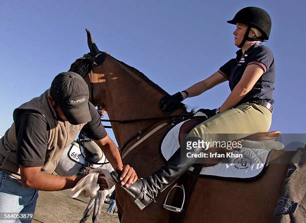 Thermal, Mar.02, 2007 . A stable hand Juan Contreras, left, wipes boots of Jessica Helm as she saddles for a jump in equestrian event going on in...
