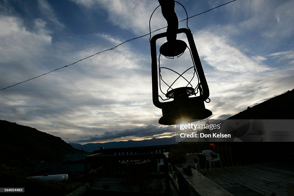 (Owens Valley)   Kerosene lantern silhouetted against evening sky, hangs outside Cerro Gordo muse