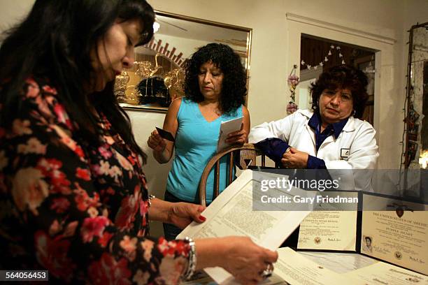 Velia Ortega , Aurora Carrera , and Irma Portillo look at photos and other military memorbilia of their brother, Specialist Juan L. Terrazas, who was...