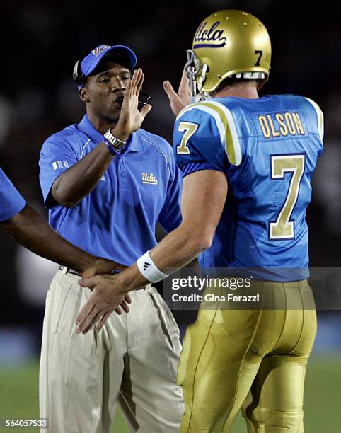 Quarterback Ben Olson gets a highfive from coach Karl Dorrell after throwing his first touchdown pass of the game in the second quarter against Rice...