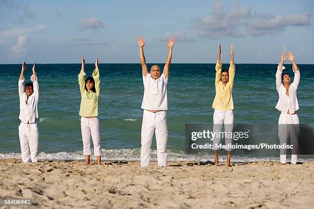 five people exercising on the beach - rolled up trousers stock-fotos und bilder