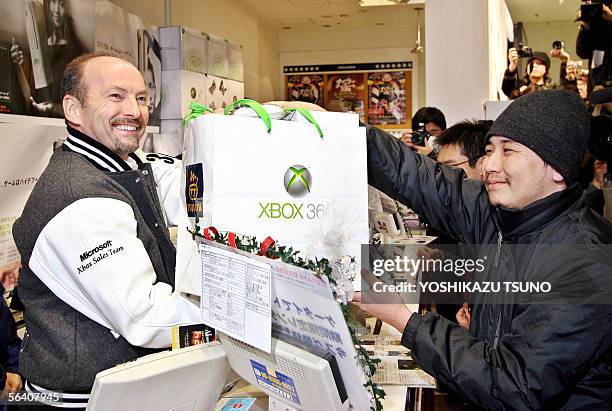 Software giant Microsoft Vice President Peter Moore delivers a package of the newly launched Xbox 360 video game console to a Japanese customer at an...