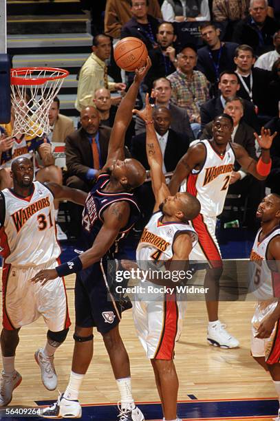 Marc Jackson of the New Jersey Nets takes the ball to the basket past Derek Fisher of the Golden State Warriors during a game at The Arena in Oakland...