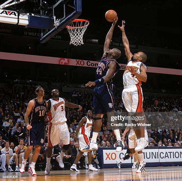 Marc Jackson of the New Jersey Nets takes the ball to the basket past Derek Fisher of the Golden State Warriors during a game at The Arena in Oakland...