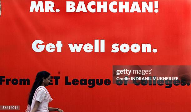 Indian students walk past a hoarding put up for Bollywood movie legend Amitabh Bachchan outside a city hospital where he is recuperating from bowel...