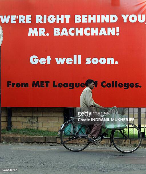 An Indian delivery man cycles past a hoarding put up for Bollywood movie legend Amitabh Bachchan outside a city hospital where he is recuperating...