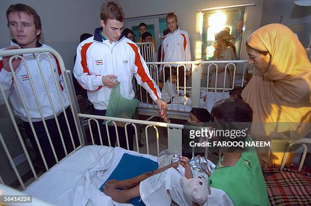 British squash player Nick Matthew gives sweets to survivors of the 08 October earth-quake asJames Willstrop and Lee Beachill look on during their...