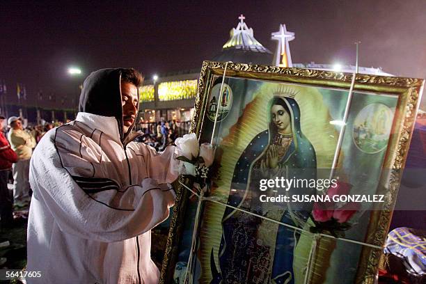 Luis Soto places a framed picture to the back of his brother during their arrival at the Basilica of Guadalupe to celebrate the day of the Mexican...