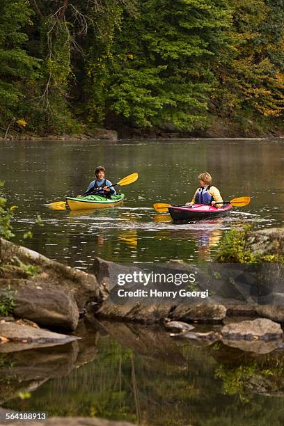 2 middle-aged women sea-kayak on farmington river near collinsville, connecticut, usa. - farmington connecticut stock-fotos und bilder