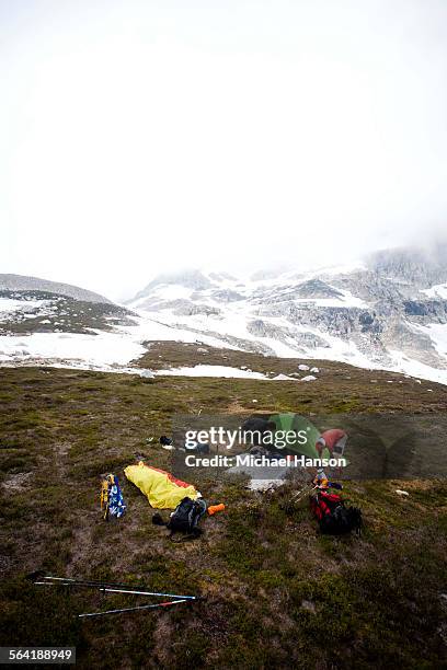 two climbers set up a campsite beneath low hanging clouds. - wildnisgebiet glacier peak stock-fotos und bilder