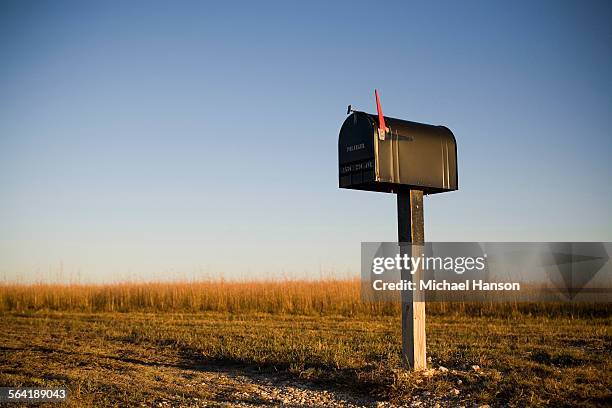 a mailbox stands alone in a kansas corn field as the sun sets beyond the horizon. - boîte aux lettres photos et images de collection