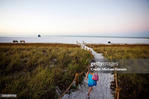 a young girl walks down a path to the beach at sunrise. - siesta key stockfoto's en -beelden
