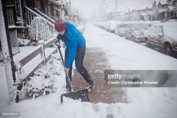 a man shovels the sidewalk outside of his suburban house. - shovel 個照片及圖片檔