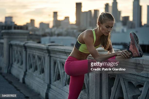 female stretching hamstrings before run - woman stretching sunset stock-fotos und bilder