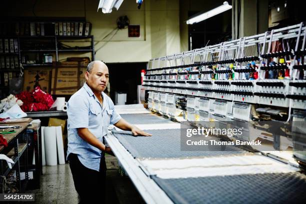worker examining project on embroidery machine - machine embroidery stock pictures, royalty-free photos & images