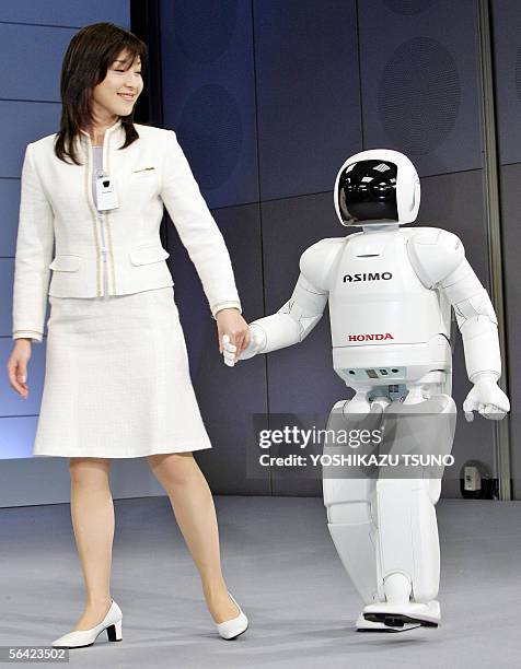 Honda Motor's new humanoid robot Asimo, which can run at a speed of 6 kph and also to run in a circular pattern, walks with a Honda employee at the...