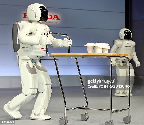 Honda Motor's new humanoid robot Asimo, which can run at a speed of 6 kph and also to run in a circular pattern, pushes a drinks tray at the...