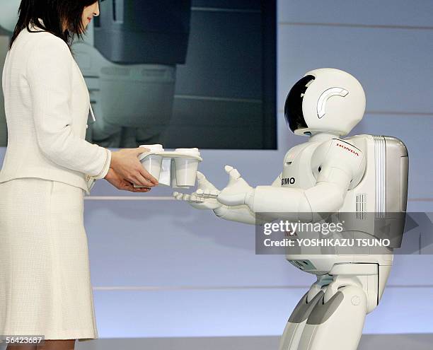 Honda Motor's new humanoid robot Asimo, which can run at a speed of 6kph and also in a circular pattern, receives cups of drink from a Honda employee...