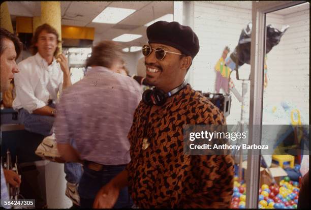 View of American film director John Singleton, in sunglasses and a beret, as he smiles on the set of his movie 'Poetic Justice,' Los Angeles,...