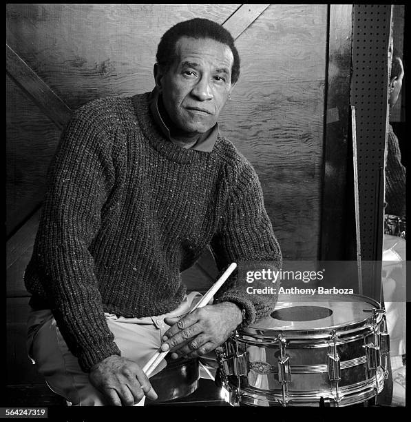 Portrait of American jazz musician Max Roach , dressed in a sweater, as he poses behind a drum kit with his drumsticks in his hands, 1989.