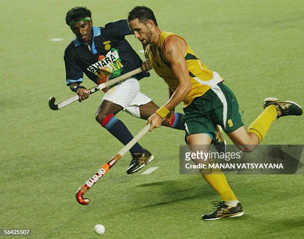 Indian field hockey player VS Vinaya chases Australian player Mark Knowles as he runs with the ball during their match in the Champions Trophy...