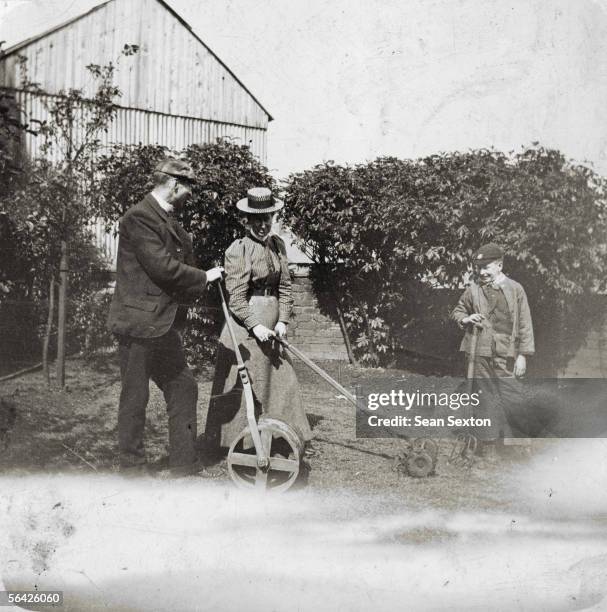 Man, woman and child try out some gardening equipment, circa 1900.