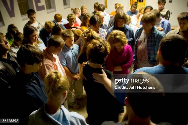 The youth group prays to bless a missionary before she goes to serve abroad during the evening service for junior high and high school students...