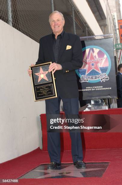 Actor Wayne Rogers poses with his star on the Hollywood Walk of Fame December 13, 2005 in Hollywood, California.