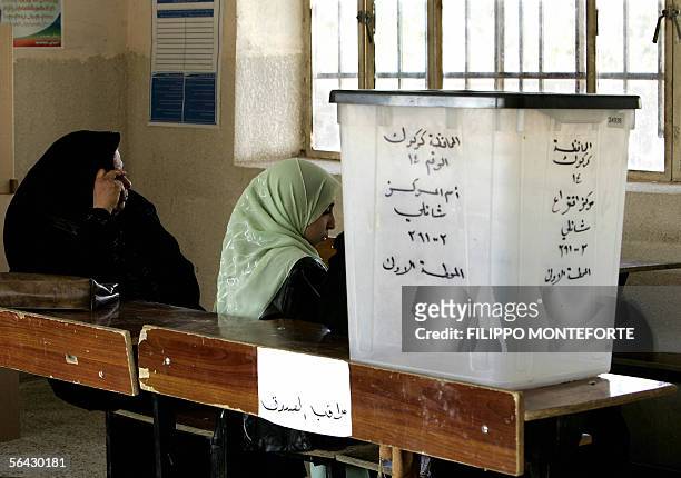 Employees of the Independent Electoral Commission in Iraq sit inside a polling station in the northern Iraqi town of Taza, 14 December 2005 on the...