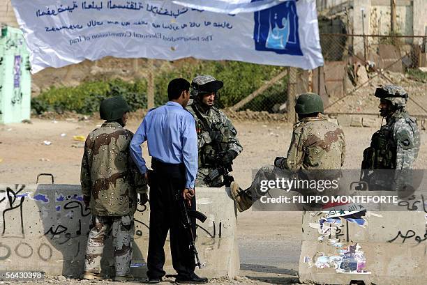 And Iraqi soldiers secuer 14 December 2005 the entrance of a polling station in the northern Iraqi town of Taza, on the eve of the country's general...