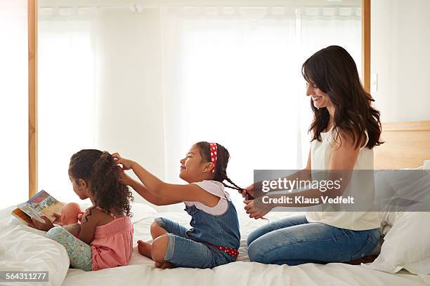 mother & 2 kids doing each others hair on a row - beautiful hair at home stock-fotos und bilder