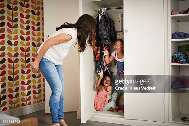 mother & daughter playing hide & seek in closet - children misbehaving stock pictures, royalty-free photos & images