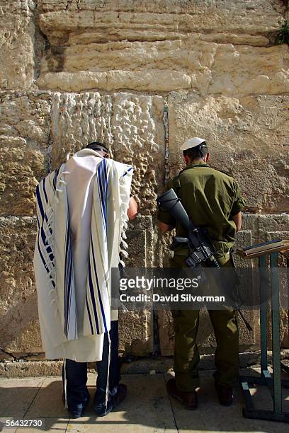Recently drafted Israeli soldier and a modern Orthodox Jew pray next to each other at the Western Wall, Judaism's holiest site, December 14, 2005 in...